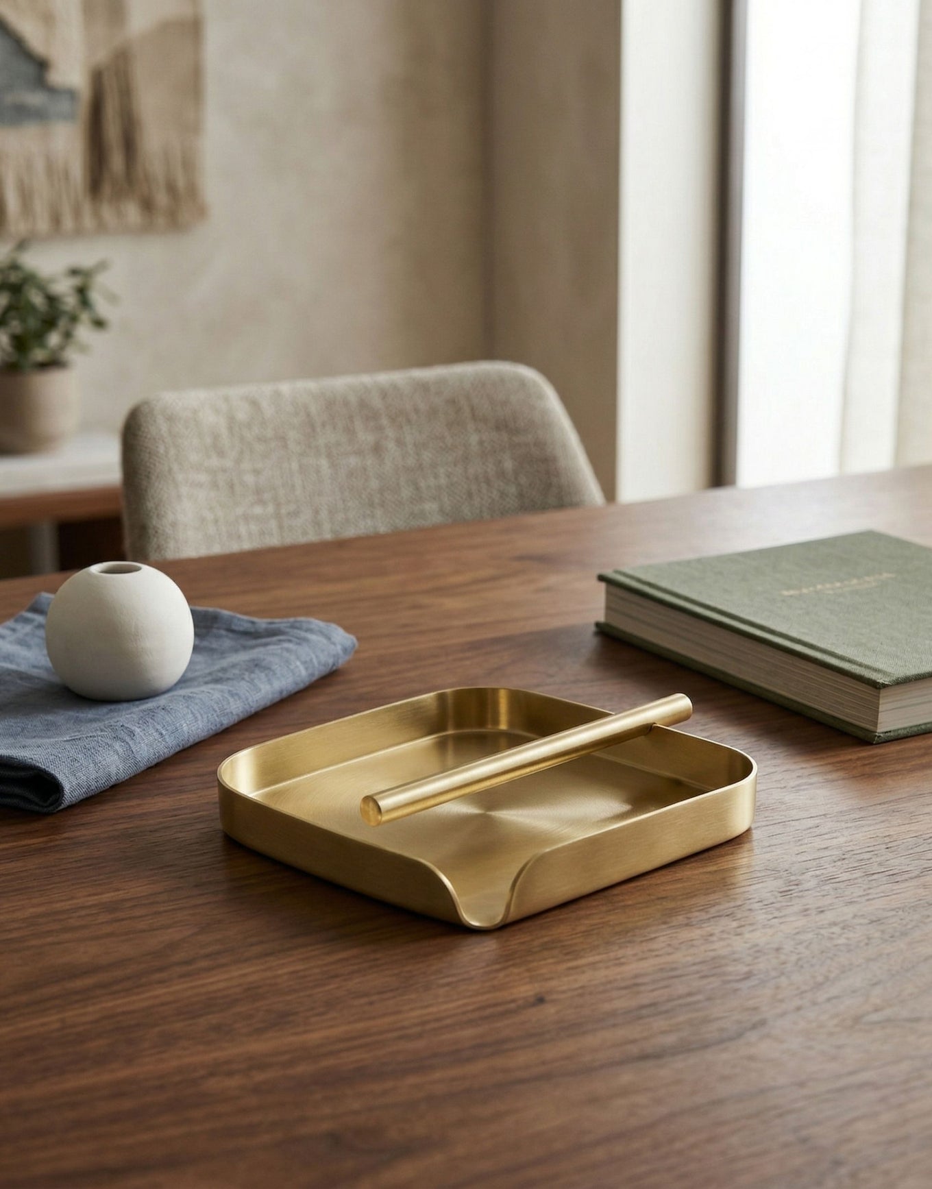 Brass tissue holder on a wooden table in a room with a chair and window.