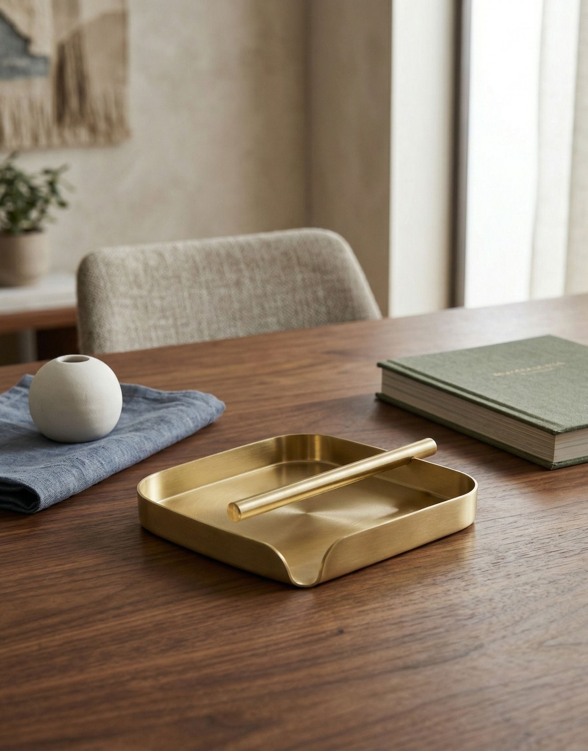 Brass tissue holder on a wooden table in a room with a chair and window.