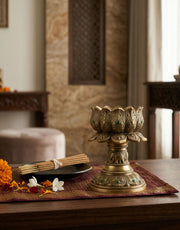 Decorative brass lotus camphor holder on a table with a blurred background