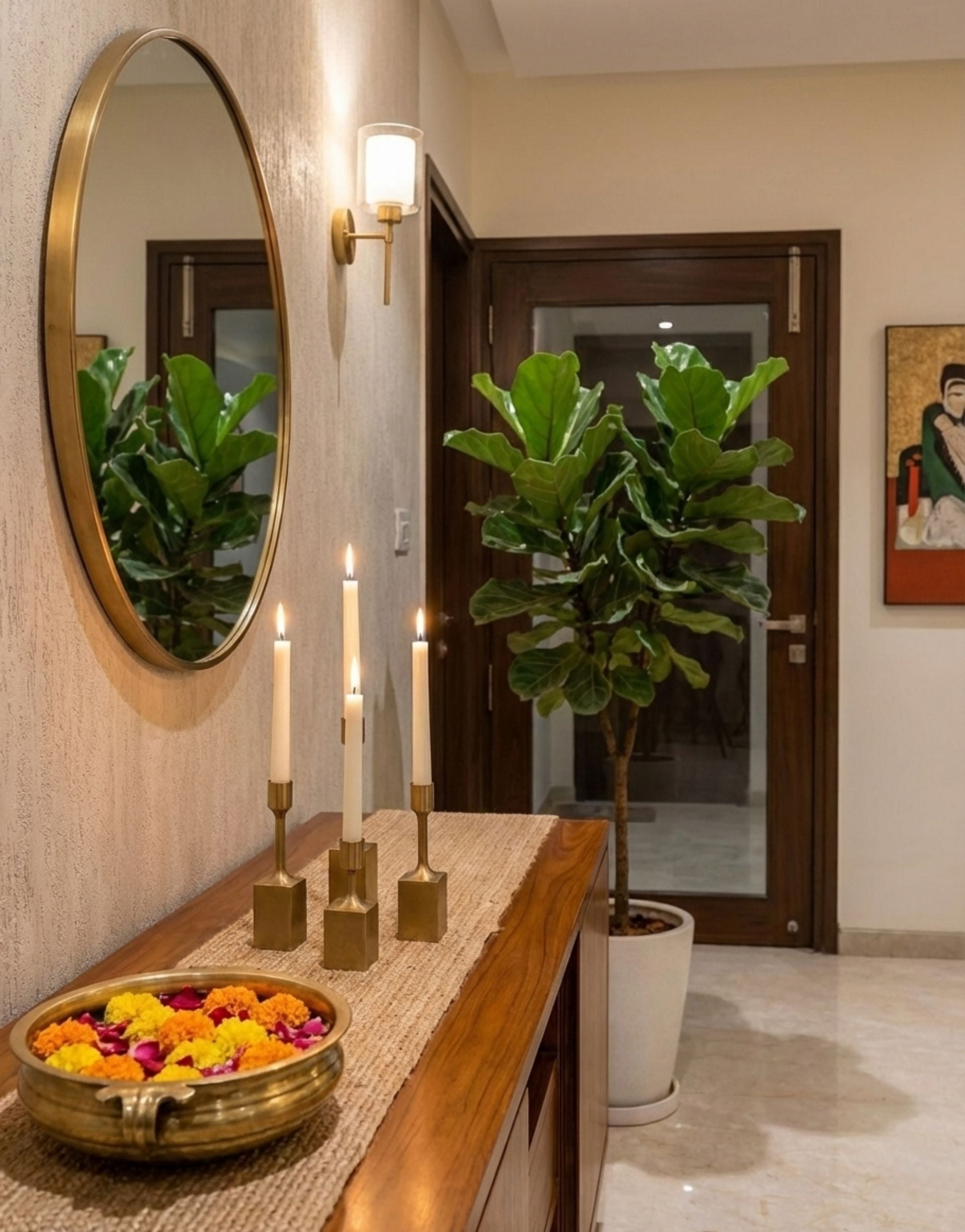 Decorative interior with a mirror, brass candles, and a plant in a room.