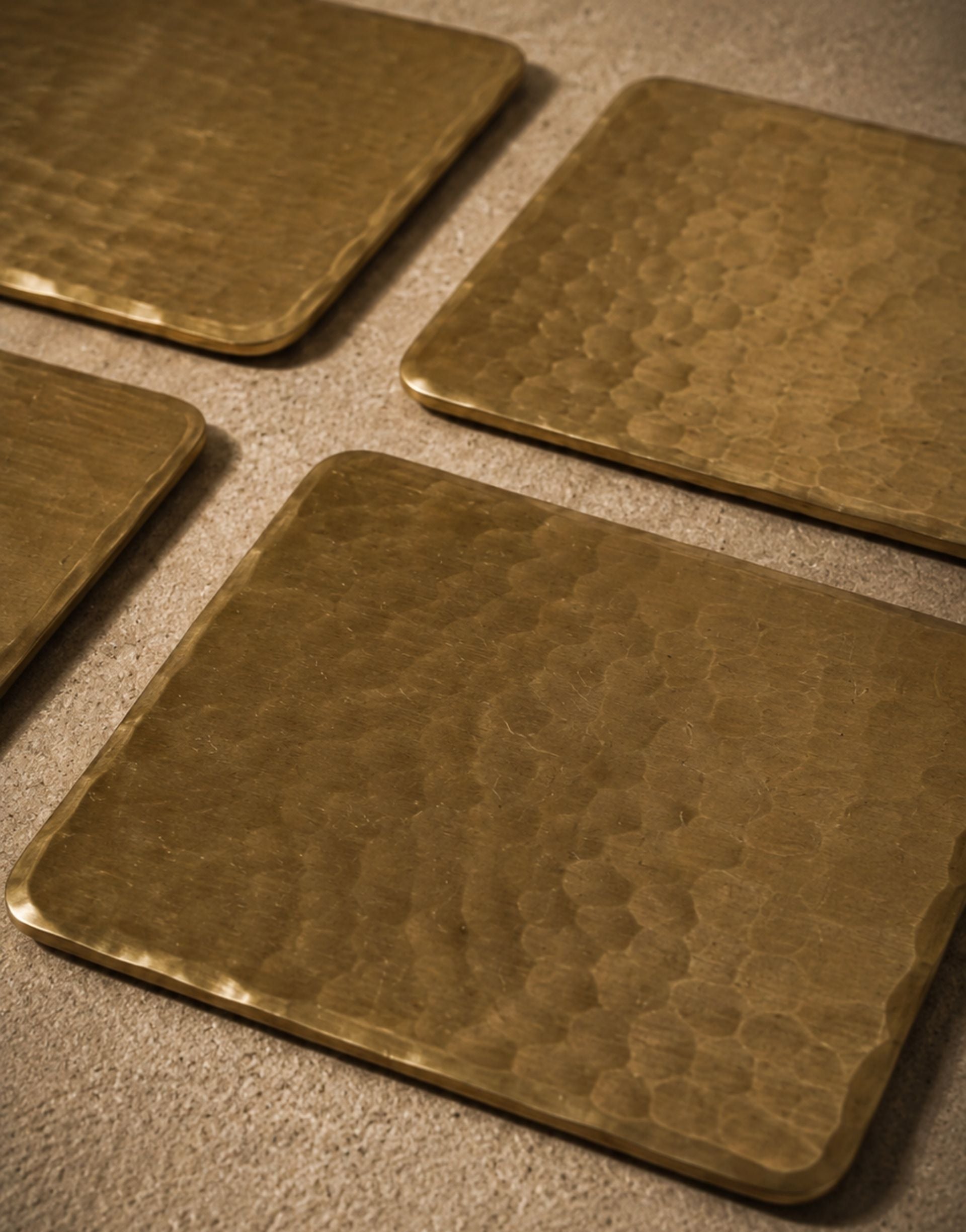 Four brass coasters with a textured surface on a matching surface.