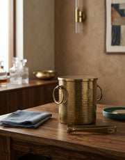 Brass ice bucket on a wooden table with a neutral background