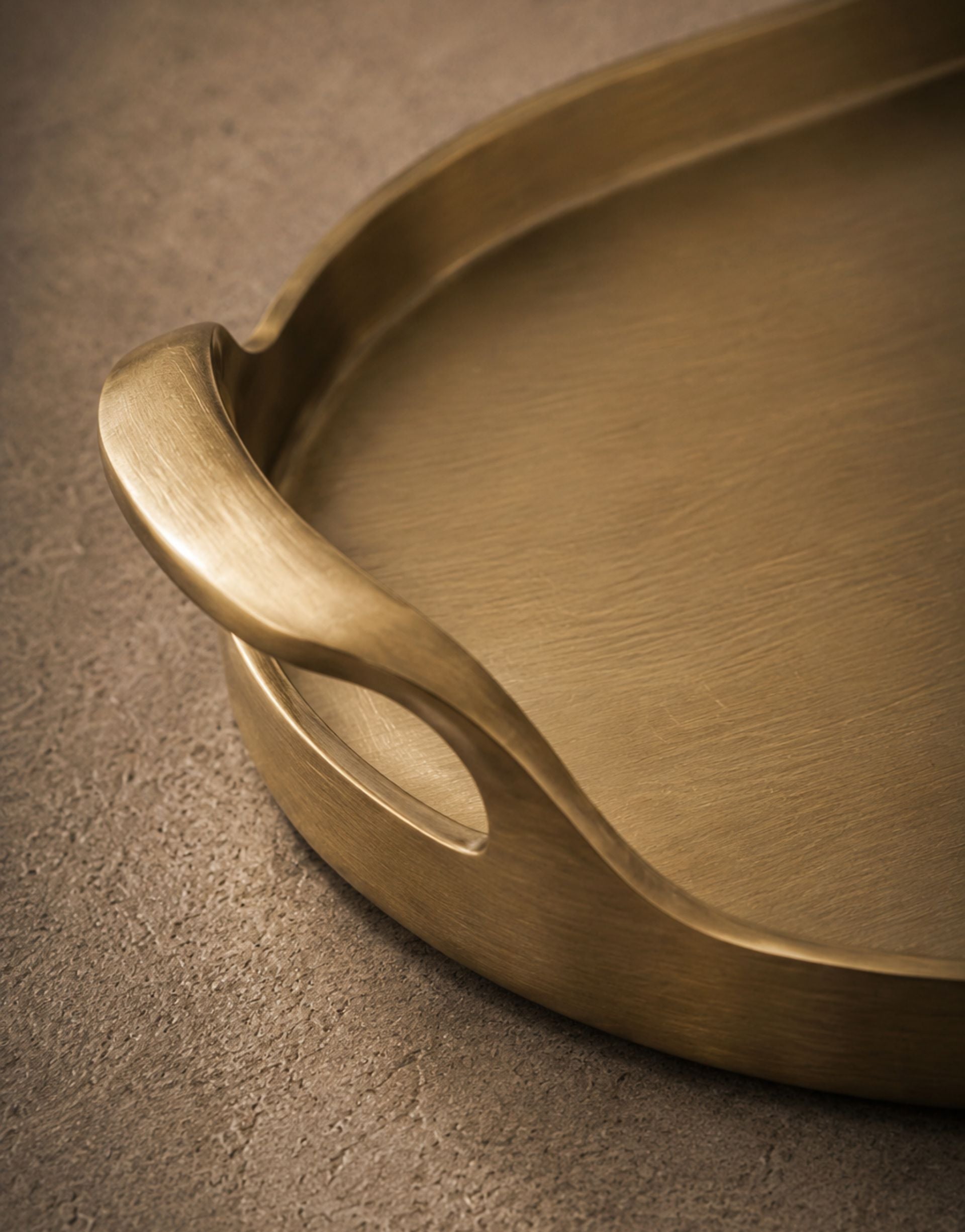 Brass serving tray with handle on a textured brown surface