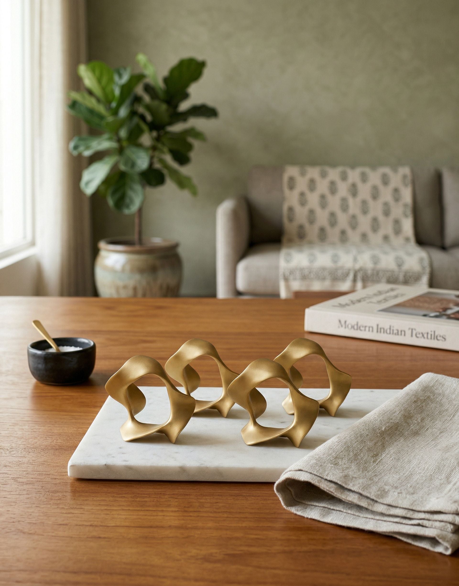 Decorative brass table napkin rings on a marble tray in a living room setting